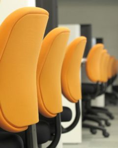 Long row of uniform desk chairs and desks