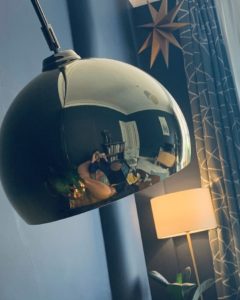 Picture of a young woman working from home reflected in a lamp shade