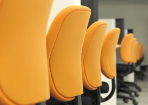 Long row of uniform desk chairs and desks