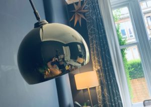 Picture of a young woman working from home reflected in a lamp shade