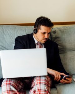 Young man working from home in pyjama bottoms and suit jacket.